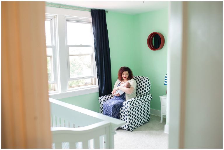 Mother snuggling with her newborn in a green modern nursery