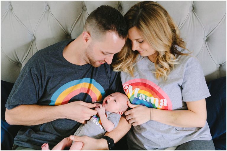 parents snuggling newborn wearing rainbow shirts