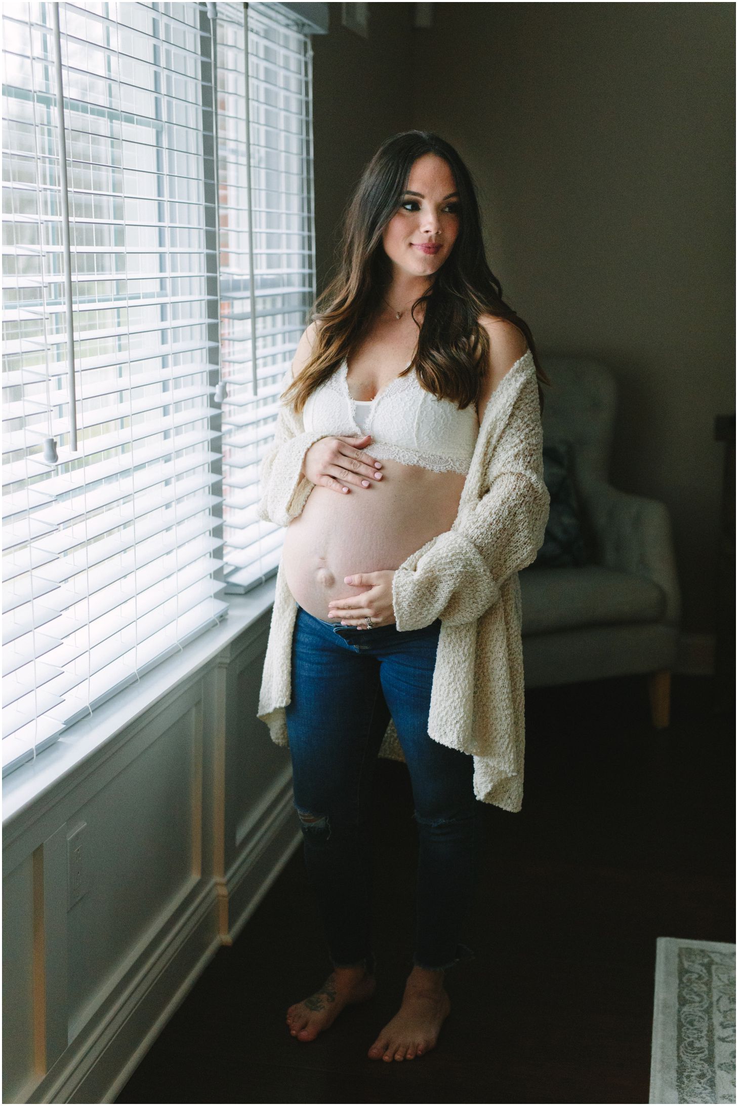 mom standing in front of a window holding belly | maternity session
