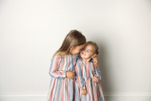 two sisters in matching dresses laughing together