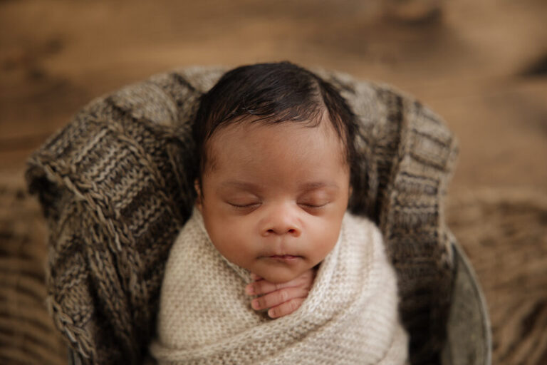 African American newborn baby boy wrapped in neutrals while sleeping
